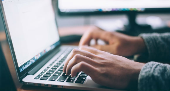 Hands typing searching the internet on laptop