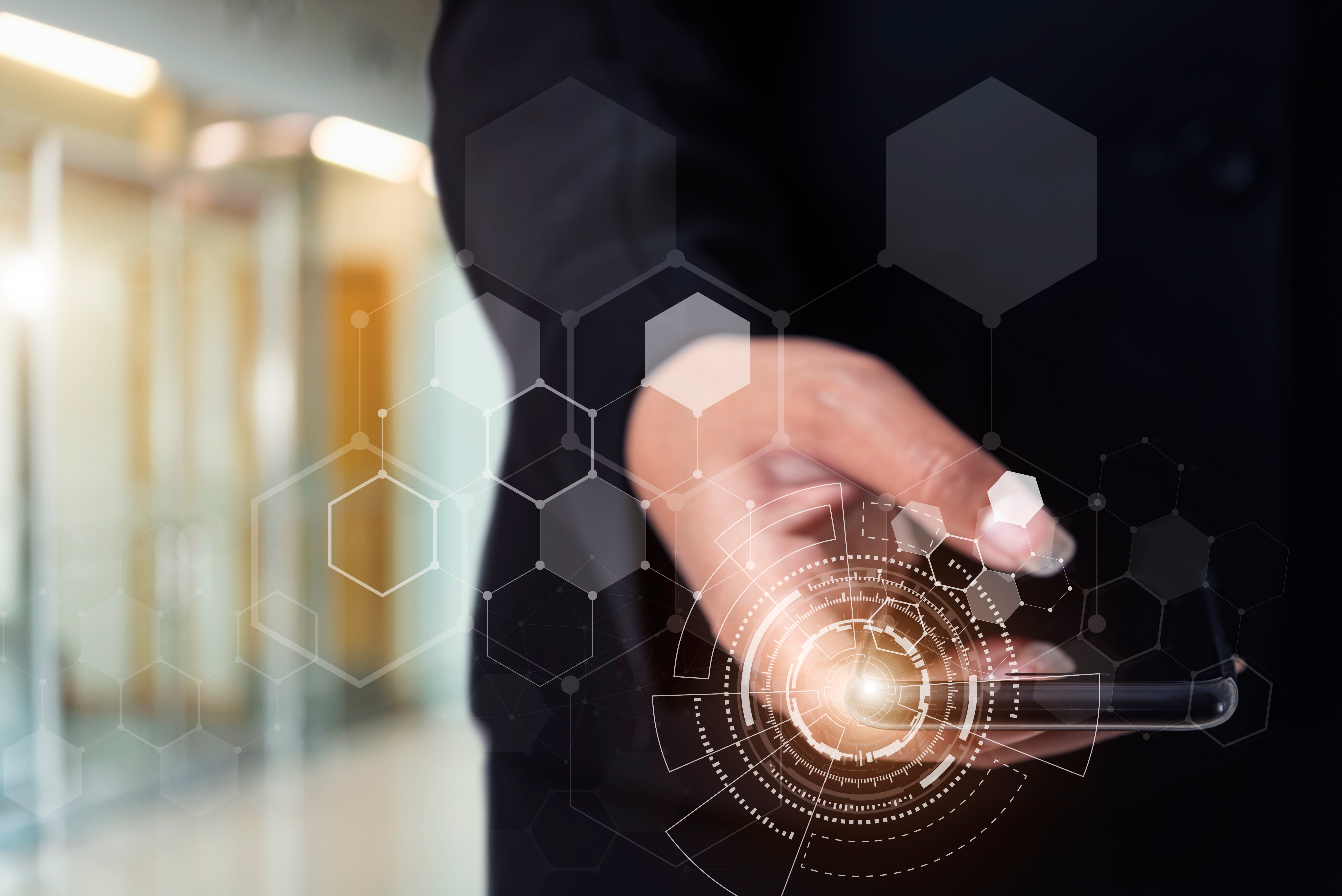 A person in a dark suit using a smartphone, with digital hexagonal graphics and a glowing circular interface overlay, symbolizing technology or data interaction.